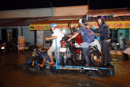 Nhiều xe ba gác máy vận chuyển xe máy của người dân qua điểm ngập sâu. (Ảnh: Mạnh Linh/TTXVN) 
