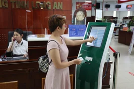 Người dân lấy số thứ tự tại Trung tâm Phục vụ Hành chính Công tỉnh Long An. (Ảnh: Minh Hưng/TTXVN)