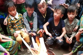 Các em học sinh trường vùng núi sưởi ấm trước khi vào lớp học. (Ảnh: Đinh Thùy/TTXVN)