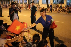 Sinh viên tình nguyện phát cờ Tổ quốc cho nhân dân. (Ảnh: Minh Sơn/Vietnam+)