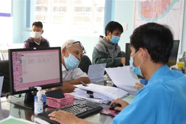 Cán bộ UBND phường Hiệp Bình Chánh, thành phố Thủ Đức giải quyết hồ sơ cho người dân. (Ảnh: Xuân Tình/TTXVN)