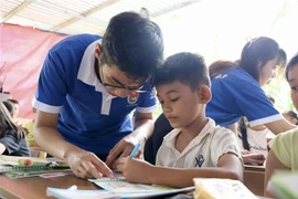 Các gia sư áo xanh tình nguyện hướng dẫn bài học học sinh. (Ảnh: Hồng Giang/TTXVN)