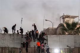 Người biểu tình trèo qua hàng rào bên ngoài Đại sứ quán Thụy Điển tại thủ đô Baghdad, Iraq. (Ảnh: AFP/TTXVN)