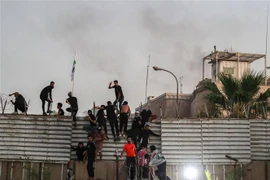 Người biểu tình trèo qua hàng rào bên ngoài Đại sứ quán Thụy Điển tại thủ đô Baghdad, Iraq. (Ảnh: AFP/TTXVN)