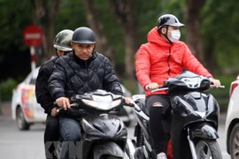 Người dân Thủ đô mặc áo ấm trên đường Đinh Tiên Hoàng (Hà Nội). (Ảnh: Danh Lam/TTXVN)