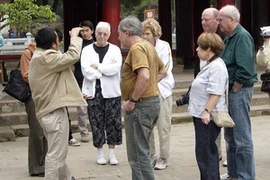 Hướng dẫn viên du lịch giới thiệu với du khách nước ngoài về một di tích ở Hà Nội. (Nguồn: TTXVN)