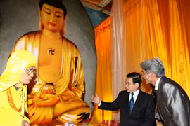 Chủ tịch nước Nguyễn Minh Triết xem phiến đá ngọc bích để chế tác tương Phật tổ Thích ca Mâu Ni. (Ảnh: Nguyễn Khang/TTXVN) 