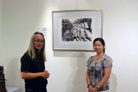 Họa sỹ Singapore, Choo Meng Foo (trái) giới thiệu với khách tham quan về tác phẩm của mình. (Ảnh: Chí Giáp/Vietnam+)
