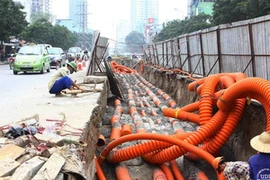 Thi công hạ ngầm tuyến cáp trên đường Lê Văn Lương, Hà Nội. (Ảnh: Hồng Kỳ/TTXVN)