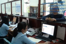 Người dân làm thủ tục tại Văn phòng một cửa. (Ảnh: Đức Thọ/ TTXVN)