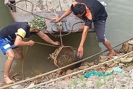 Lực lượng chức năng tiến hành trục vớt quả bom trên sông Đuống. (Ảnh TTXVN phát)