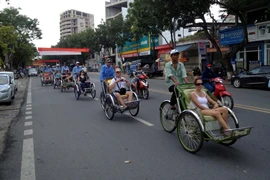 Khách du lịch quốc tế tham quan thành phố Huế trên phương tiện xích lô. (Ảnh: Quốc Việt/TTXVN)