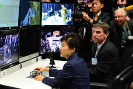 Tổng thống Hàn Quốc Park Geun-hye (giữa) điều khiển một cánh tay robot trong chuyến thăm Trung tâm Goddard. (Ảnh: Yonhap/TTXVN)