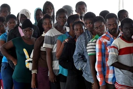 Người di cư xếp hàng nhận đồ ăn trên tàu Hải quân Đức sau khi được cứu vớt trên biển Địa Trung Hải ngày 27/9 vừa qua. (Ảnh: AFP/TTXVN)