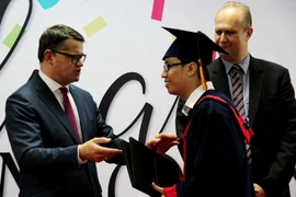 Bộ trưởng Bộ Khoa học và Nghệ thuật Cộng hòa liêng bang Đức Boris Rhein (trái) trao bằng tốt nghiệp cho sinh viên. (Ảnh: Dương Chí Tưởng/TTXVN)
