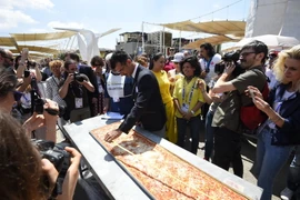 Nhân viên của Sách kỷ lục Guinness đo chiều dài chiếc bánh pizza tại Hội chợ triển lãm EXPO ở Milan. (Ảnh: AFP/TTXVN)