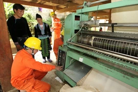 Công nhân Công ty Điện lực Lai Châu thuộc Tổng công ty Điện lực miền Bắc hướng dẫn bà con dân tộc sử dụng điện an toàn trong sản xuất. (Ảnh: Ngọc Hà/TTXVN)