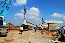 Đơn vị thi công đang tiến hành lao lắp dầm nhịp dẫn cầu Bến Đình. (Ảnh: Lê Đức Hoảnh/TTXVN)