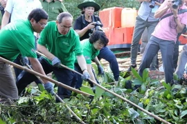 Bí thư Thành ủy Thành phố Hồ Chí Minh Nguyễn Thiện Nhân (thứ 2 từ trái qua) tham gia dọn rác trên kênh Rạch Lăng. (Ảnh: Xuân Dự/TTXVN)