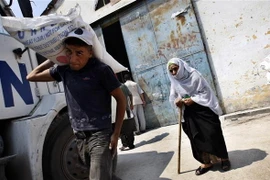Người dân Palestine nhận lượng thực cứu trợ của UNRWA tại trại tị nạn Rafah ở Dải Gaza. (Nguồn: AFP/TTXVN)