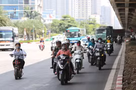 Người tham gia giao thông phải tránh nắng dưới bóng râm của gầm cầu trên tuyến đường Phạm Hùng. (Ảnh: Thành Đạt/TTXVN)