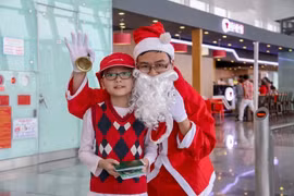 Hành khách nhí chụp hình và nhận món quà từ Ông già Noel của Cảng hàng không Nội Bài. (Ảnh: Dương Phạm/Vietnam+)