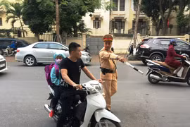 Cảnh sát giao thông phát hiện phụ huynh chở con em đều không đội mũ bảo hiểm. (Ảnh: Việt Hùng/Vietnam+)