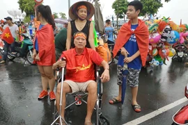 ông Đinh Anh Tuấn ở Sóc Sơn, Hà Nội vẫn "vịn" xe lăn xuống đường đón đoàn thể thao Việt Nam. (Ảnh: Sơn Bách/Vietnam+)
