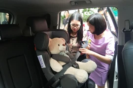 Phụ huynh thực hành cài dây an toàn ở ghế ngồi sau. (Ảnh: Việt Hùng/Vietnam+)