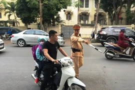 Cảnh sát giao thông phát hiện phụ huynh chở con em đều không đội mũ bảo hiểm. (Ảnh: Việt Hùng/Vietnam+)