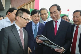 Chủ tịch nước Trần Đại Quang xem một ấn phẩm của TTXVN. (Ảnh: Lê Minh Sơn/Vietnam+)