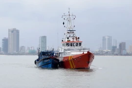 Một tàu cá gặp nạn được lai dắt vào bờ. (Ảnh: Nguyễn Sơn/TTXVN)