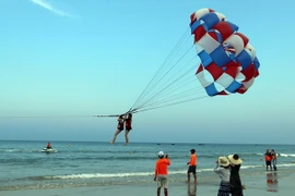 Khách du lịch tham gia trò chơi canô kéo dù tại biển Phạm Văn Đồng (Đà Nẵng). (Ảnh: Trần Lê Lâm/TTXVN)