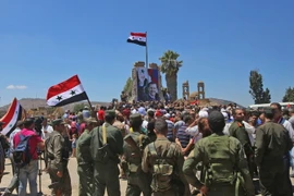 Binh sĩ quân đội chính phủ Syria giương cao quốc kỳ sau khi giải phóng thành phố Quneitra ngày 27/7. (Ảnh: AFP/TTXVN)