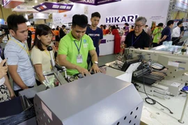 Khách tham quan gian trưng bày máy cắt may tự động tại một triển lãm về công nghiệp dệt, may, thiết bị và nguyên liệu. (Ảnh: Trần Việt/TTXVN)