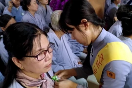 Nghi thức "Bông hồng cài áo" trong lễ Vu Lan ở Việt Nam. (Ảnh: Kim Há/TTXVN)