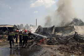 Lính cứu hỏa phun nước làm nguội hiện trường vụ cháy. (Ảnh: Thành Chung/TTXVN)