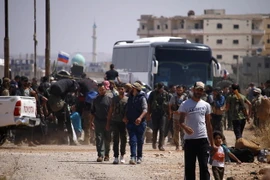 Các tay súng phiến quân cùng gia đình chuẩn bị rời thành phố Daraa để tới những khu vực do phe đối lập kiểm soát tại miền bắc Syria ngày 15/7. (Ảnh: AFP/TTXVN)