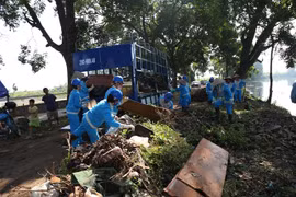 Công nhân vệ sinh môi trường đô thị Gia Lâm thực hiện thu gom rác thải bên bờ sông Cầu Bây. (Ảnh Mạnh Khánh/TTXVN)