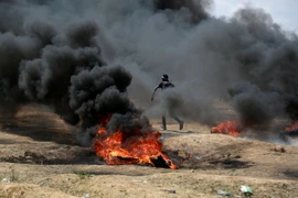  Người Palestine đốt lốp xe trong cuộc biểu tình tại khu vực biên giới Dải Gaza với Israel. (Nguồn: THX/TTXVN)