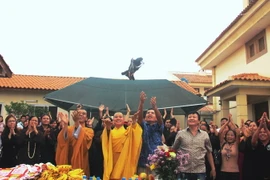 Đại sứ Nguyễn Mạnh Cường, Đại đức Thích Minh Huệ và bà con cộng đồng người Việt thực hiện nghi thức thả chim phóng sinh. (Ảnh: TTXVN)