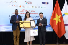 Phó Tổng giám đốc TTXVN Lê Quốc Minh và Trưởng đại diện khu vực châu Á-Thái Bình Dương của Tổ chức quốc tế Pháp ngữ OIF Chékou Oussouman trao giải Nhất cho tác giả Man Khánh Ly. (Ảnh: Hoàng Hiếu/TTXVN)