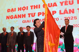 Chủ tịch Quốc hội Nguyễn Thị Kim Ngân gắn Huân chương Lao động hạng Nhất lên lá cờ truyền thống của ngành Tư pháp. (Ảnh: Doãn Tấn/TTXVN)