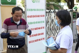 Nhân viên y tế phát khẩu trang cho một số người dân chưa tuân thủ việc đeo khẩu trang phòng, chống dịch bệnh. (Ảnh: Tuấn Đức/TTXVN)