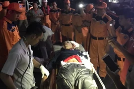 Hỗ trợ ngư dân bị thương sau khi đưa về bờ. (Ảnh: Nguyên Lý/TTXVN)