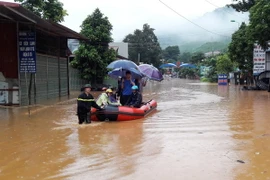 Lực lượng chức năng dùng xuồng đưa người dân vượt qua đoạn ngập sâu tại thị trấn Ít Ong, huyện Mường La. (Ảnh: Nguyễn Cường/TTXVN)