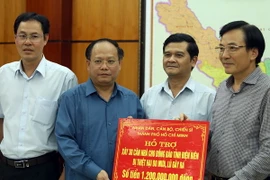 Ông Tất Thành Cang (thứ 2 từ trái sang) trao tặng bảng tượng trưng số tiền hỗ trợ cho đồng bào bị mưa lũ. (Ảnh: Phan Tuấn Anh/TTXVN)