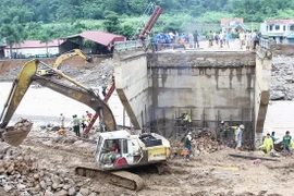 Huy động sức người và máy xúc làm đường qua suối Nặm Păm. (Ảnh: Nguyễn Cường/TTXVN)