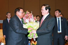 Chủ tịch Hội Hữu nghị Việt Nam-Lào Vũ Trọng Kim tặng hoa Tổng Bí thư, Chủ tịch nước Lào. (Ảnh: Doãn Tấn/TTXVN)