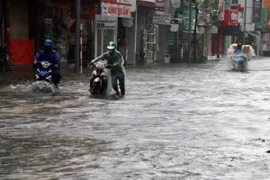 Nước ngập tại nhiều tuyến đường trong thành phố Huế khiến việc đi lại của người dân khó khăn. (Ảnh: Đỗ Trưởng/TTXVN)